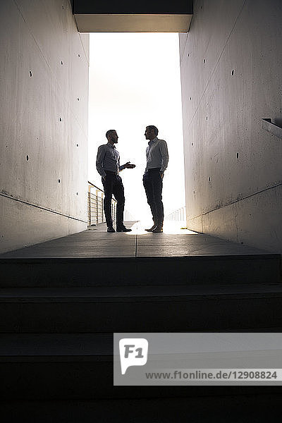 Two businessmen talking in a passageway
