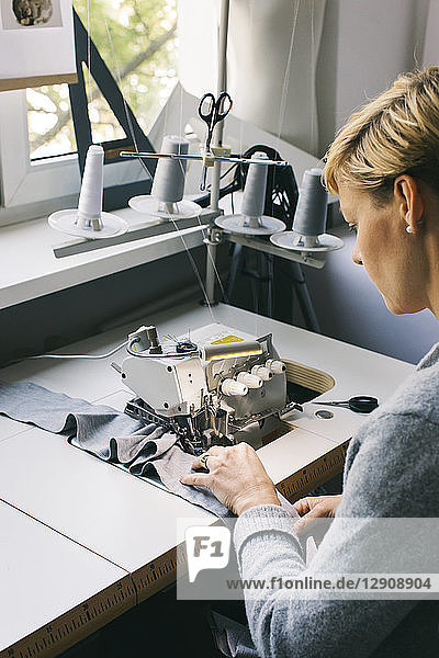 Woman using sewing machine on table in studio