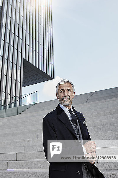 Portrait of fashionable businessman in front of stairs