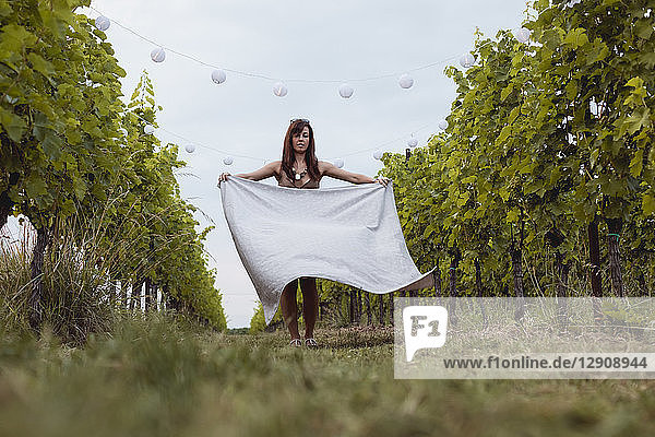 Woman spreading picnic blanket in decorated vineyard