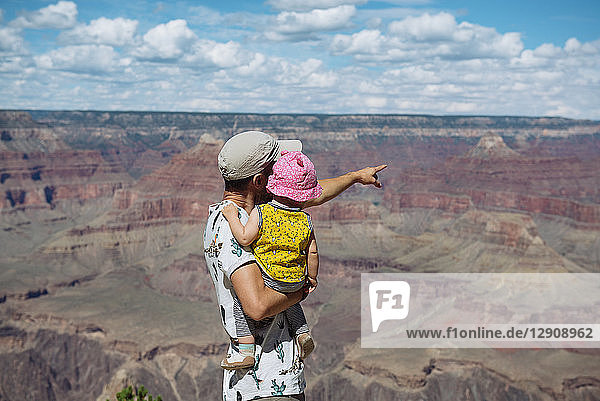 USA  Arizona  Grand Canyon National Park  father and baby girl enjoying the view  rear view
