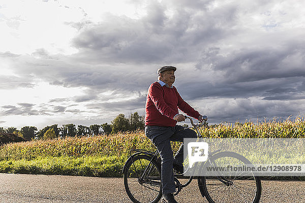 Senior man riding bicycle on country lane