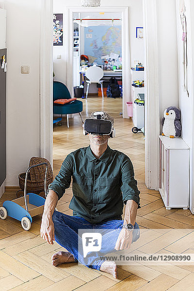 Mature man sitting on the floor at home using Virtual Reality Glasses