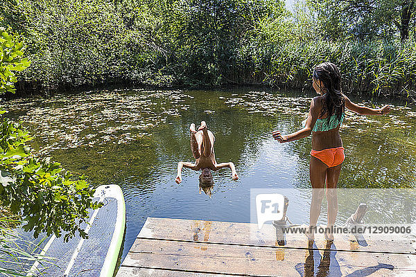 Girl watching her friend jumping into pond