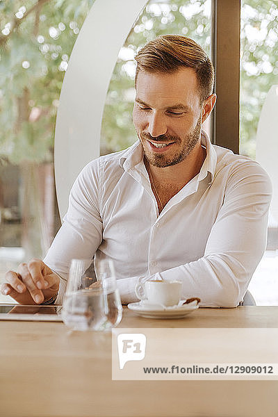 Smiling man with tablet in a cafe