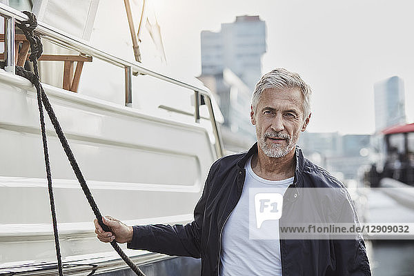 Confident mature man at a marina next to a yacht