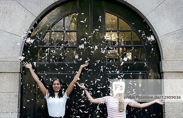 Two happy girlfriends throwing petals