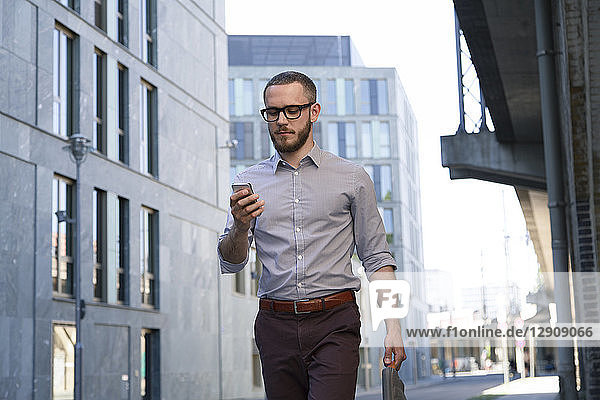 Businessman looking at cell phone in the city