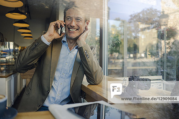 Mature businessman sitting in coffee shop  using smartphone