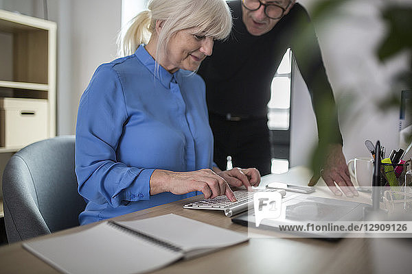 Two senior colleagues working together at desk in office
