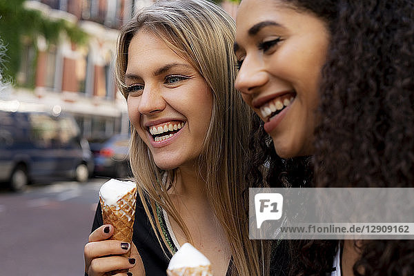 Two laughing girlfriends having fun  eating ice cream