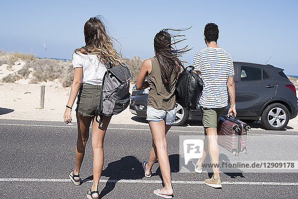 Friends crossing road  carrying bags  going to the beach