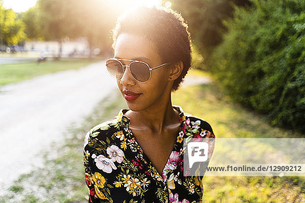 Fashionable young woman wearing sunglasses outdoors at sunset