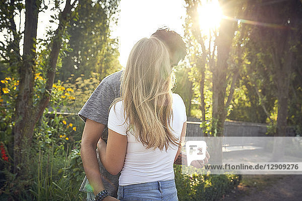 Happy young couple embracing and kissing in a park in summer