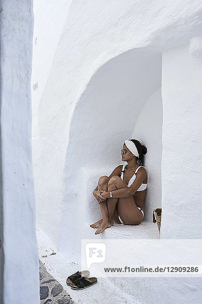 Young woman wearing white bikini sitting in a wall niche