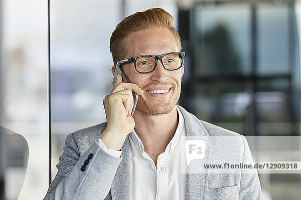 Portrait of smiling redheaded businessman on cell phone