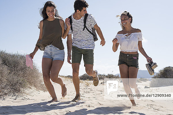 Friends having fun  running barefoot on the beach