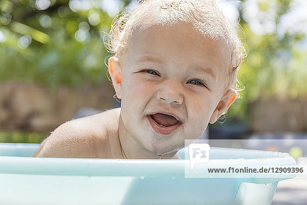 Boy sitting in baby bathtub