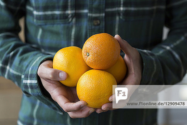 Man's hands holding four oranges  close-up