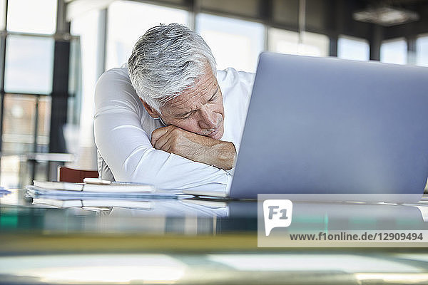 Exhausted businessman sleeping in front of laptop