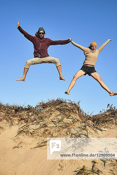 Portugal  Algarve  couple on the beach jumping down dune