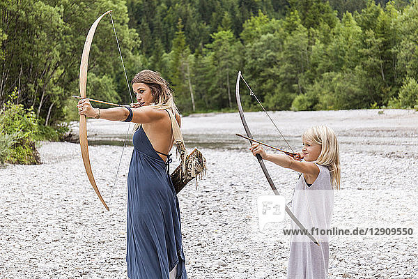Mother and daughter aiming with bow and arrow in the nature