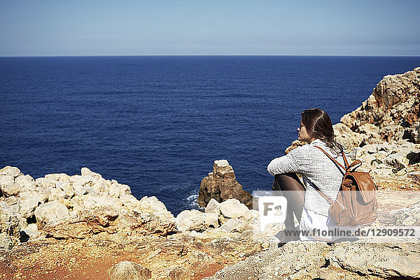 Young brunette woman sitting on coast  looking at view