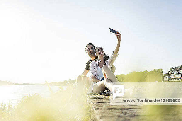 Happy couple at the riverside in summer taking a selfie