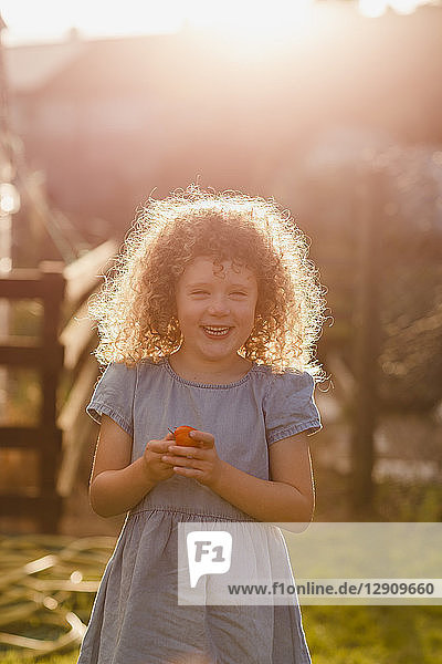 Portrait of little girl standing at backlight in the garden