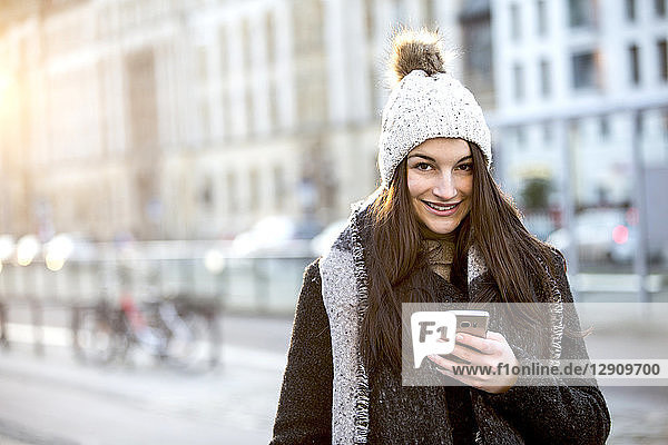 Portrait of smiling young woman with cell phone in winter, Portrait of smiling young woman with cell phone in winter
