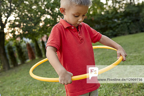 Boy playing with hula hoop in garden