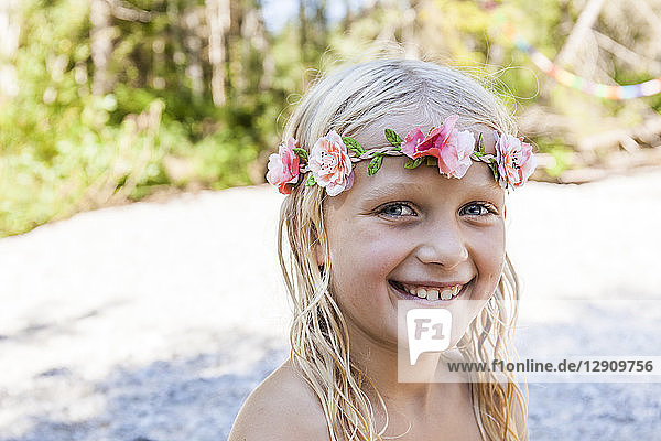 Portrait of happy girl wearing flower crown outdoors in summer
