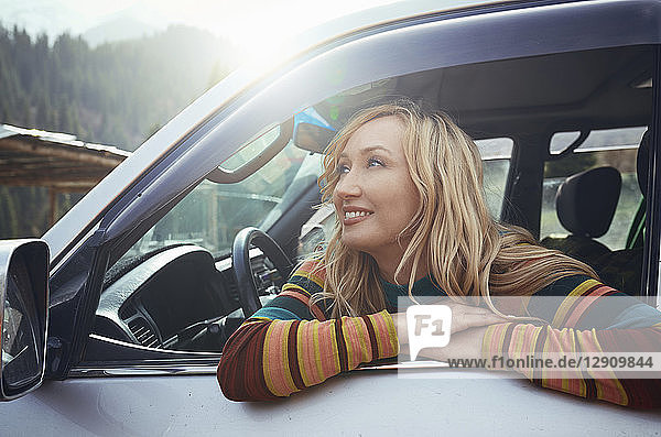 Woman sitting in car  looking at view on a road trip