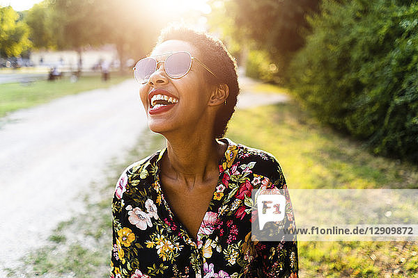 Laughing young woman wearing sunglasses outdoors at sunset