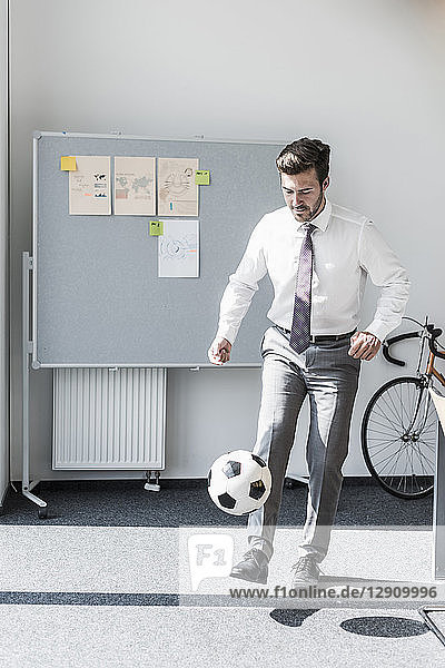 Businessman playing football in office