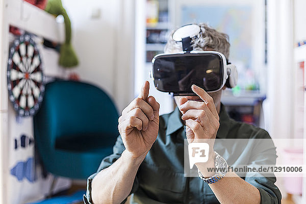 Portrait of mature man at home using Virtual Reality Glasses