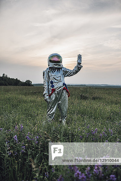 Spaceman exploring nature  standing in meadow  waving