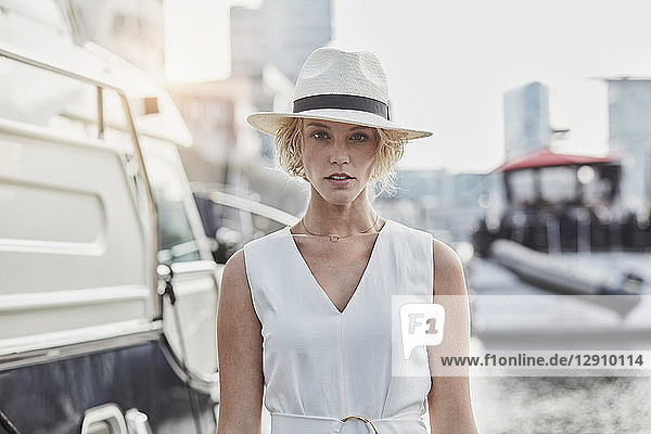 Portrait of serious young woman wearing a hat at a marina next to a yacht