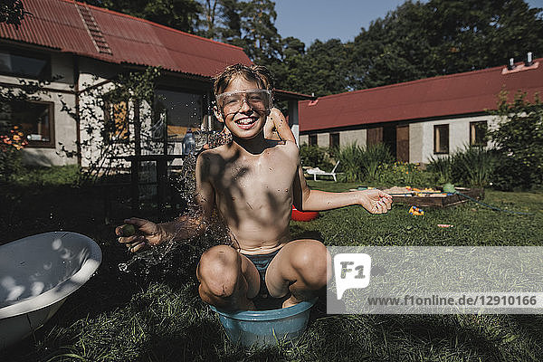 Happy brother and sister playing with water in garden
