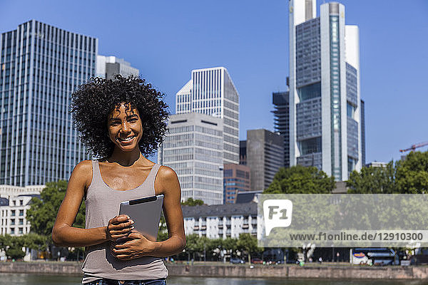 Germany  Frankfurt  portrait of smiling young woman with digital tablet in the city