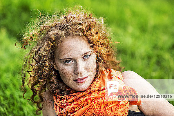 Portrait of freckled young woman with curly red hair wearing orange scarf