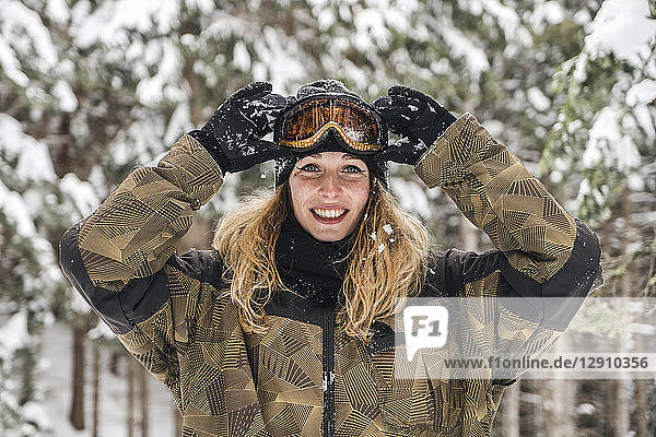 Portrait of happy young woman in skiwear in winter forest