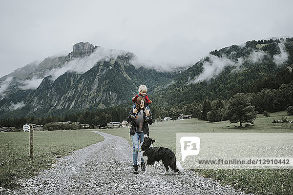 Austria  Vorarlberg  Mellau  mother carrying toddler on shoulders on a trip in the mountains