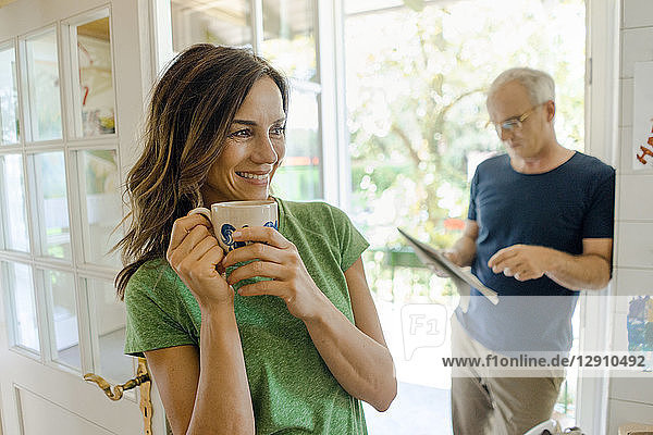 Mature couple at home with woman drinking coffee and man reading newspaper