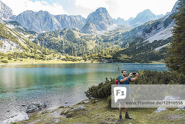 Austria  Tyrol  Hiker taking selfies with his smartphone at Lake Seebensee