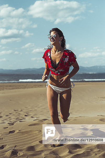 Portrait of laughing teenage girl running on the beach