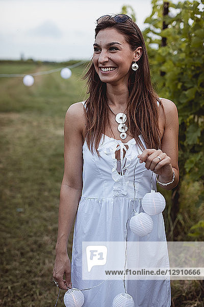 Young woman decorating vineyard with fairy lights for a picnic