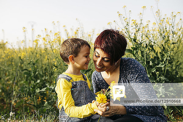 Mother and little son with picked flowers in a field
