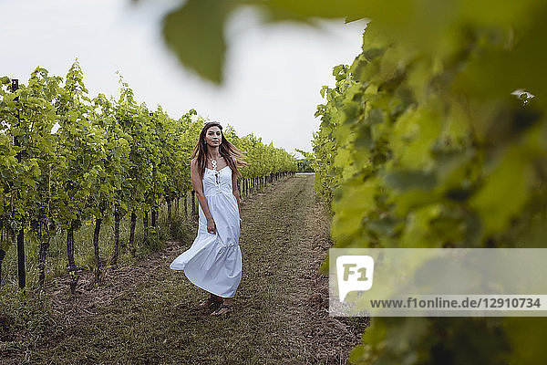 Woman wearing white summer dress  dancing in vineyard