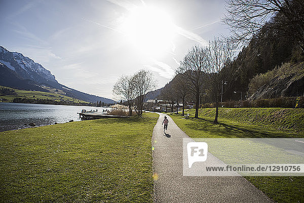 Austria  Tyrol  Walchsee  girl running on path at the lake